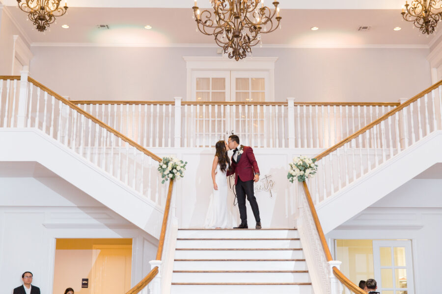 Bride and Groom kiss on the grand staircase at Kendall Point