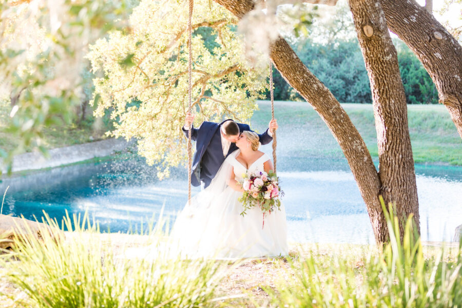 Bride and groom kiss on swing in front of Kendall Point lake.