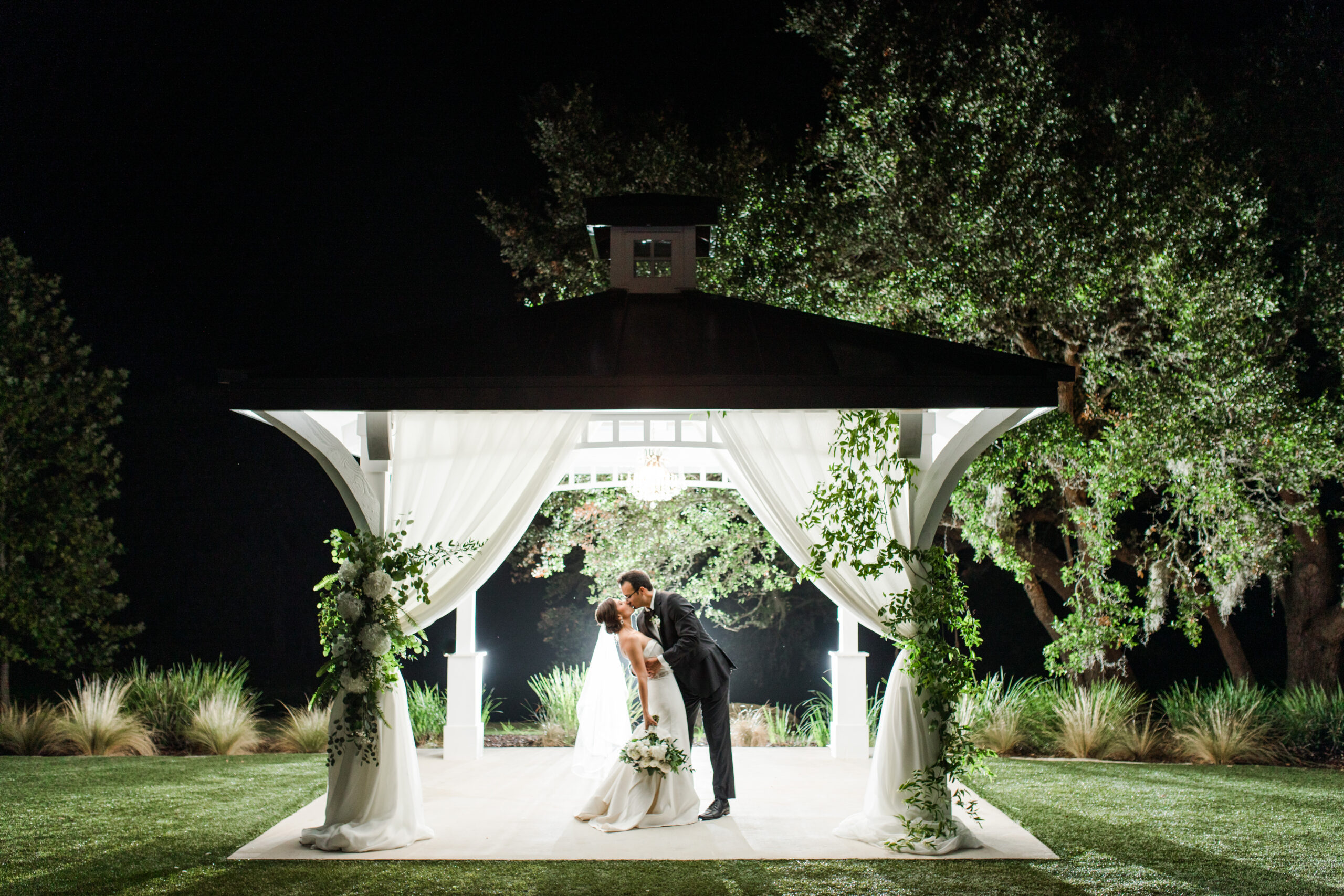 bride and groom kiss under lighted Kendall Point gazebo at night