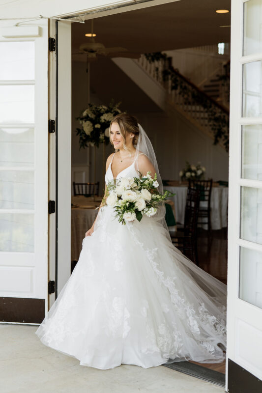 Bride carrying white flowers with green accents at emerald green wedding