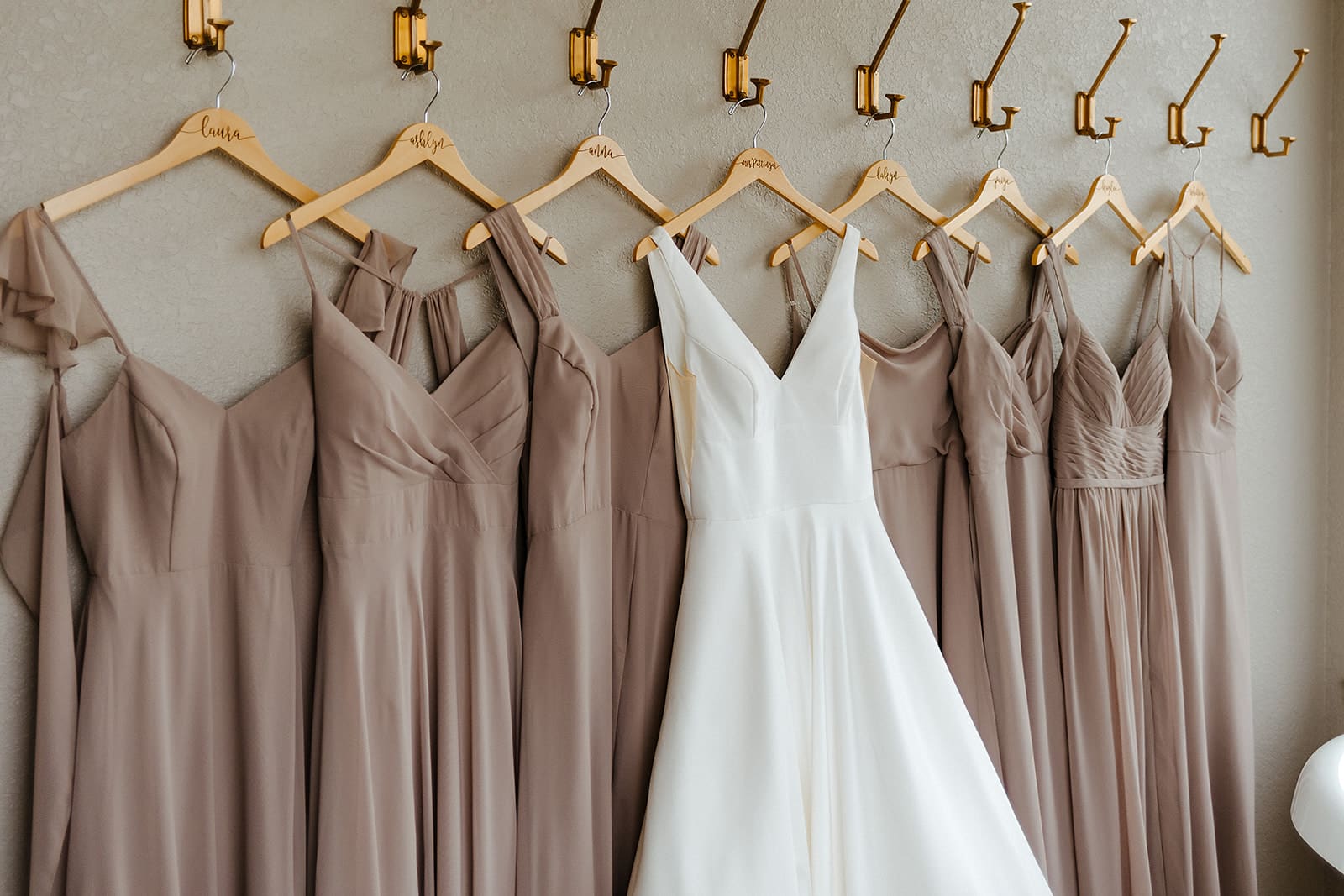 wedding gown and bridesmaids dresses hanging on hooks