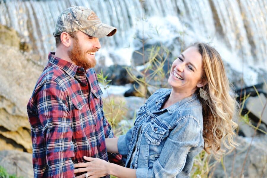 Engaged couple smiling for engagement photos at a waterfall