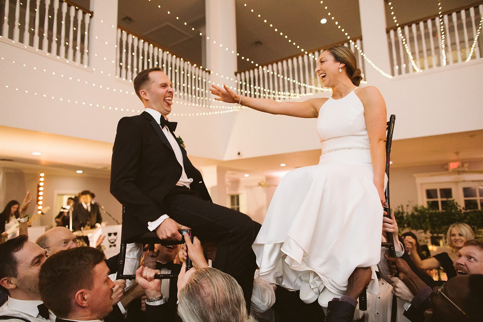 guests lifting bride and groom on chairs during the Jewish wedding tradition of dancing the hora