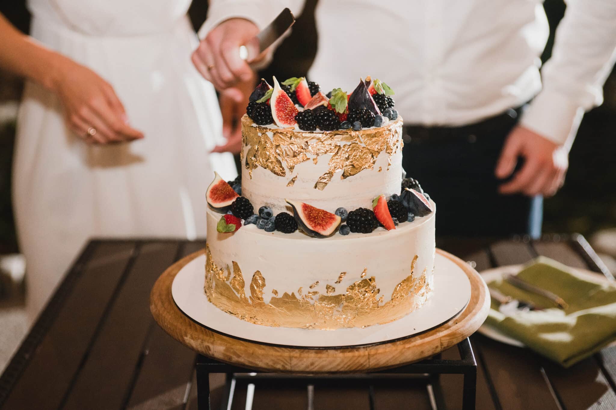 bride and groom cutting into wedding cake topped with fruit