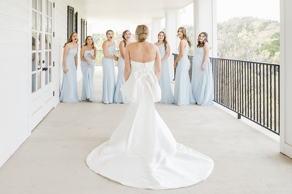 Bridesmaids scream with excitement upon seeing bride in her gown.