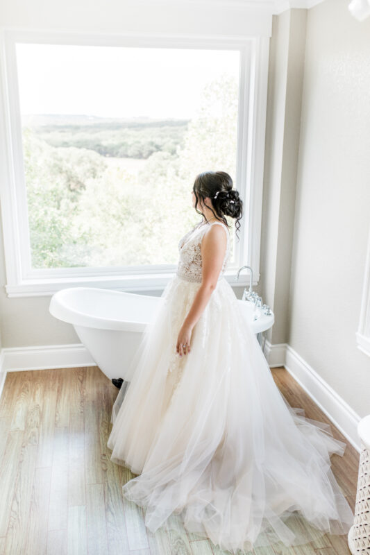 A bride stands next to the clawfoot tub in the bridal suite.
