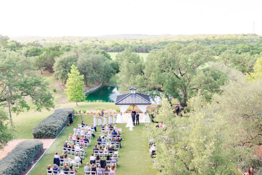 A view of the wedding from the balcony gives a view of the gazebo, lake and surrounding trees.