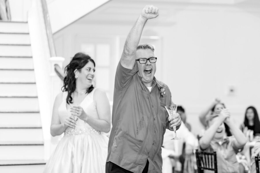 Black and white photo and bride and groom cheering during their reception