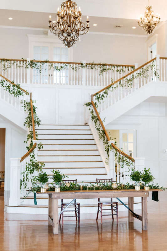 Lots of greenery adorns the sweetheart table at the foot of the staircase.