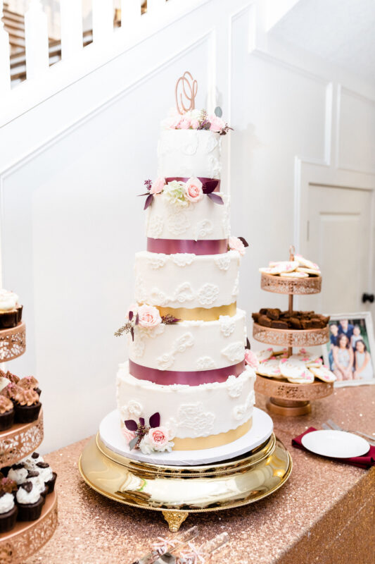 The wedding cake with pink ribbon and flowers.