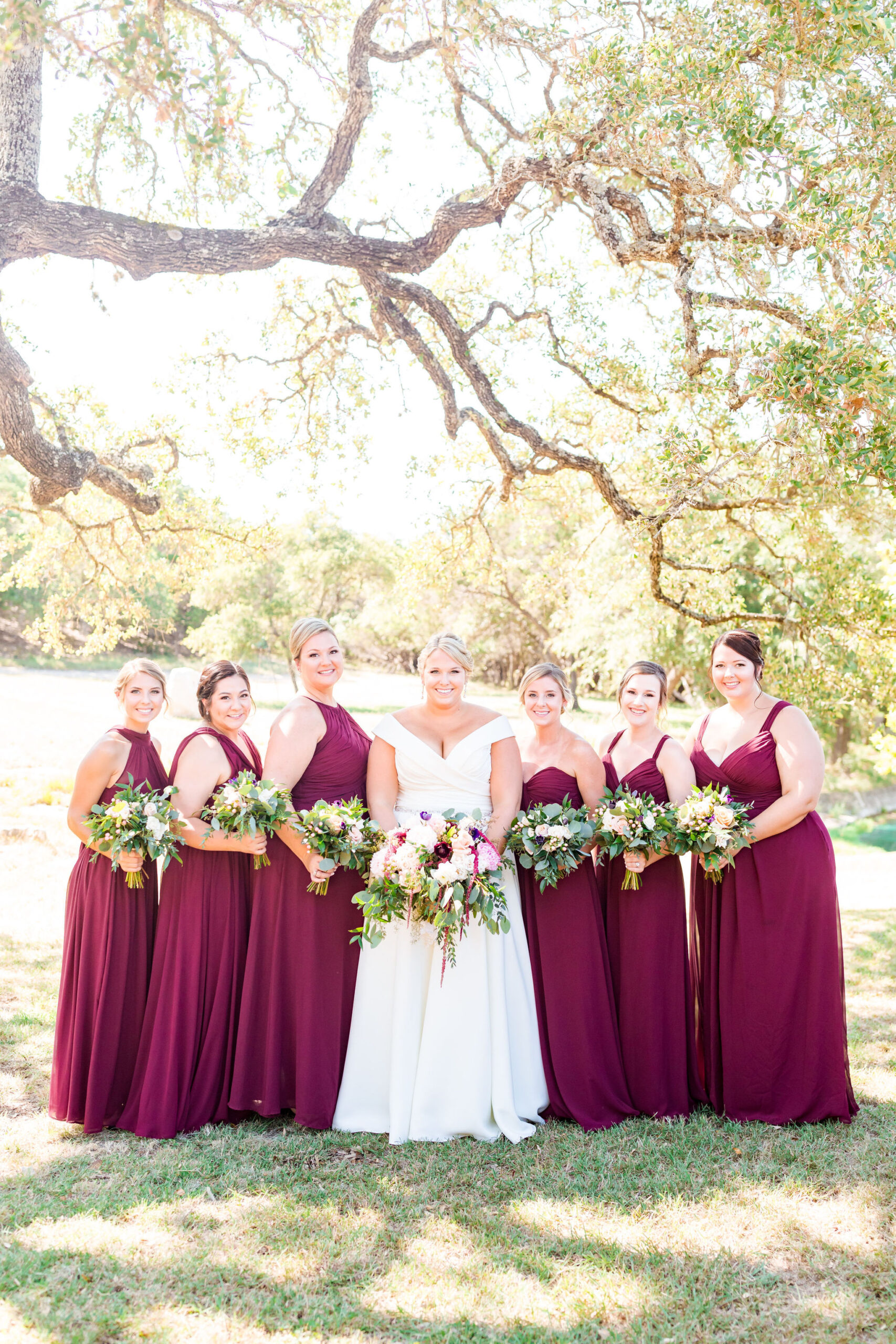 bride flanked by bridesmaids in burgundy dresses