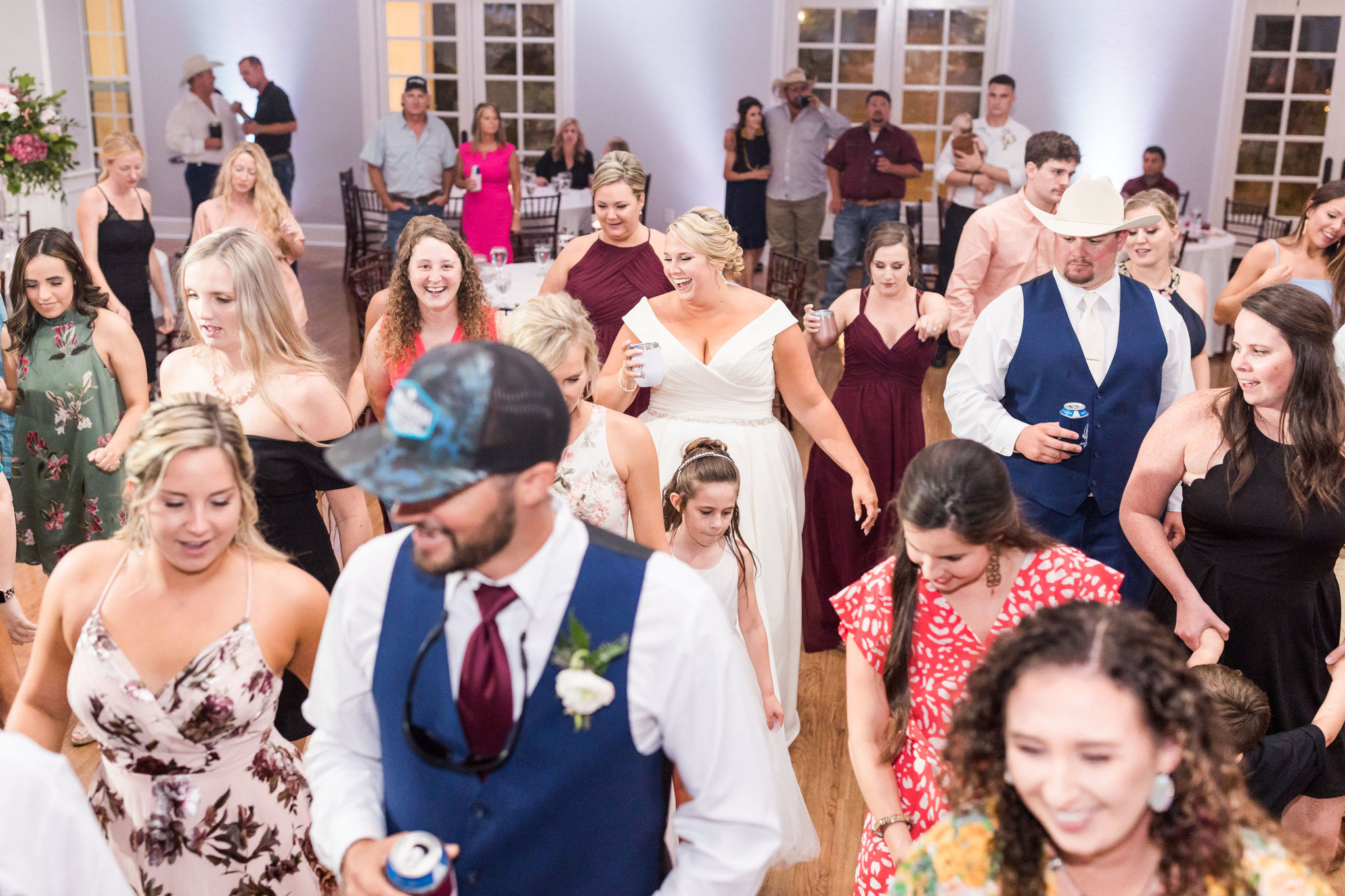 Bride and groom do a line dance with their wedding guests. 