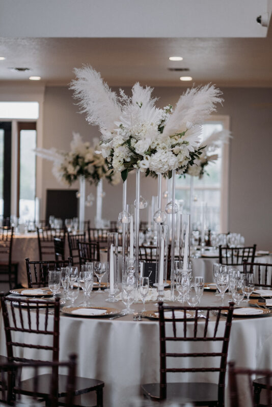 Tall glass centerpieces with white flowers and feathers. 