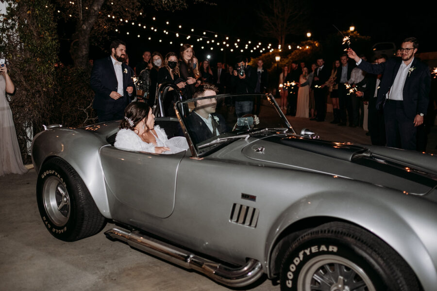 Bride and groom exit in a classic car.