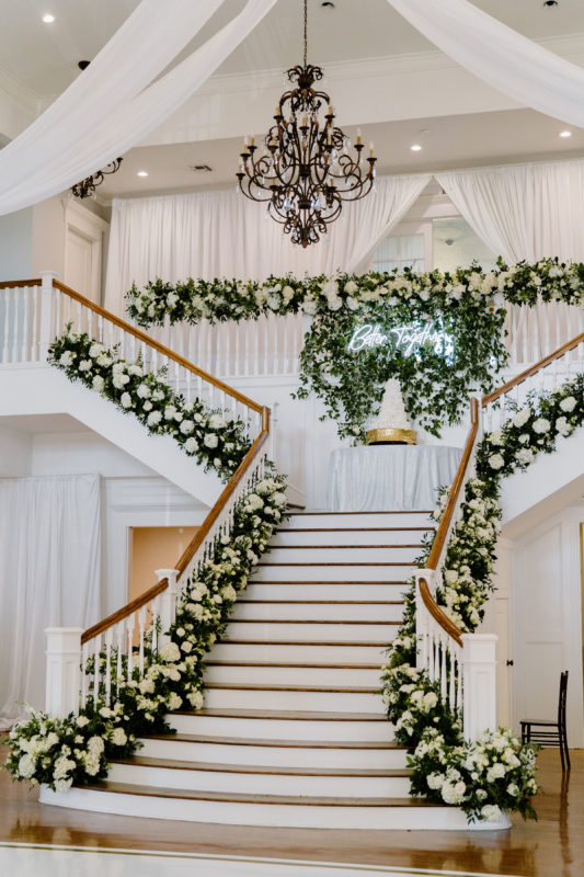 Flowers adorn the staircase in the Kendall Point ballroom and the cake table.