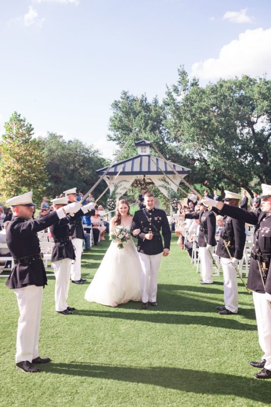 Bride and groom walk down the aisle as marines draw their swords.