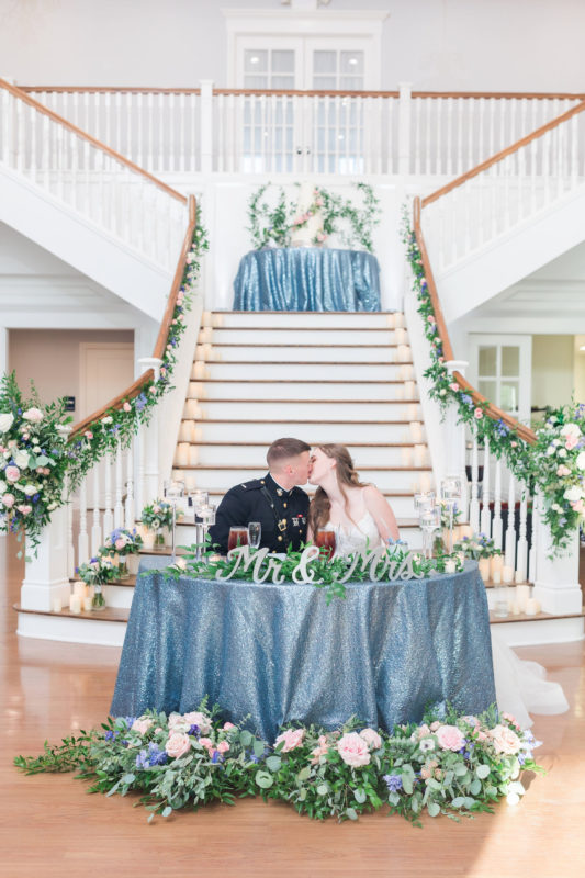 The couple kiss at the sweetheart's table.