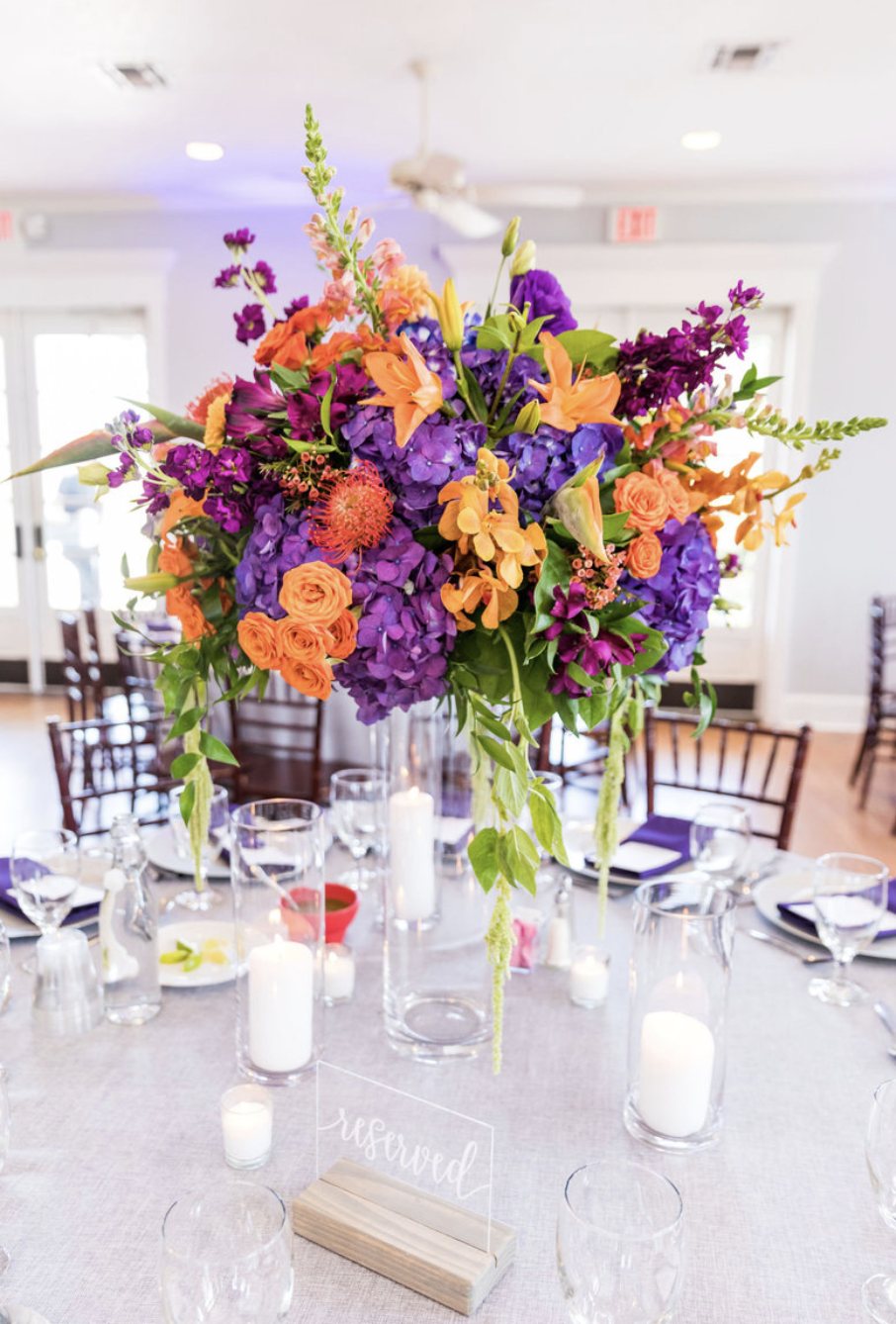 A tall and bright centerpiece of purple, orange and green flowers makes the perfect summer wedding accent.