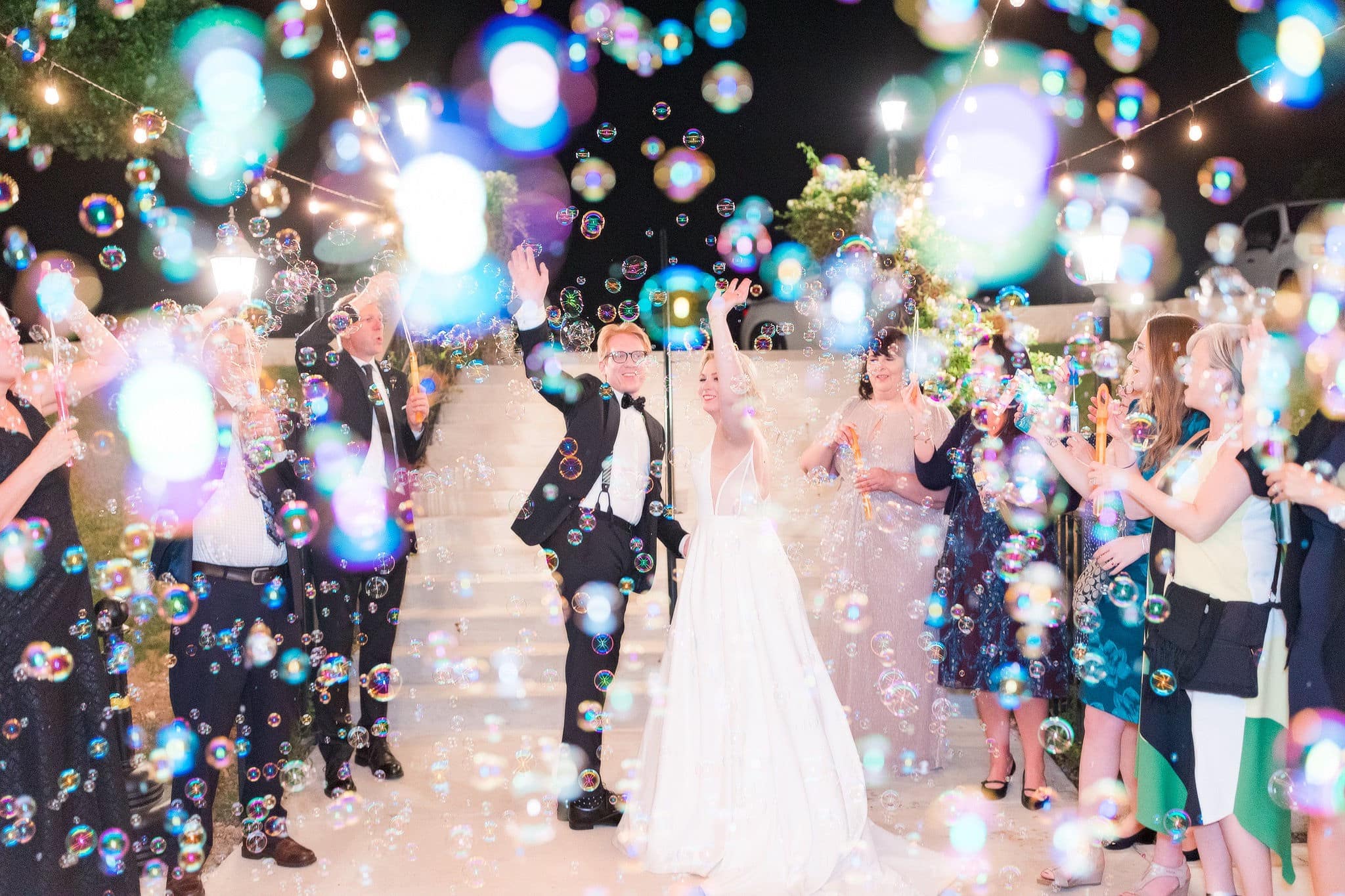 Bride and groom make grand exit under string lights.