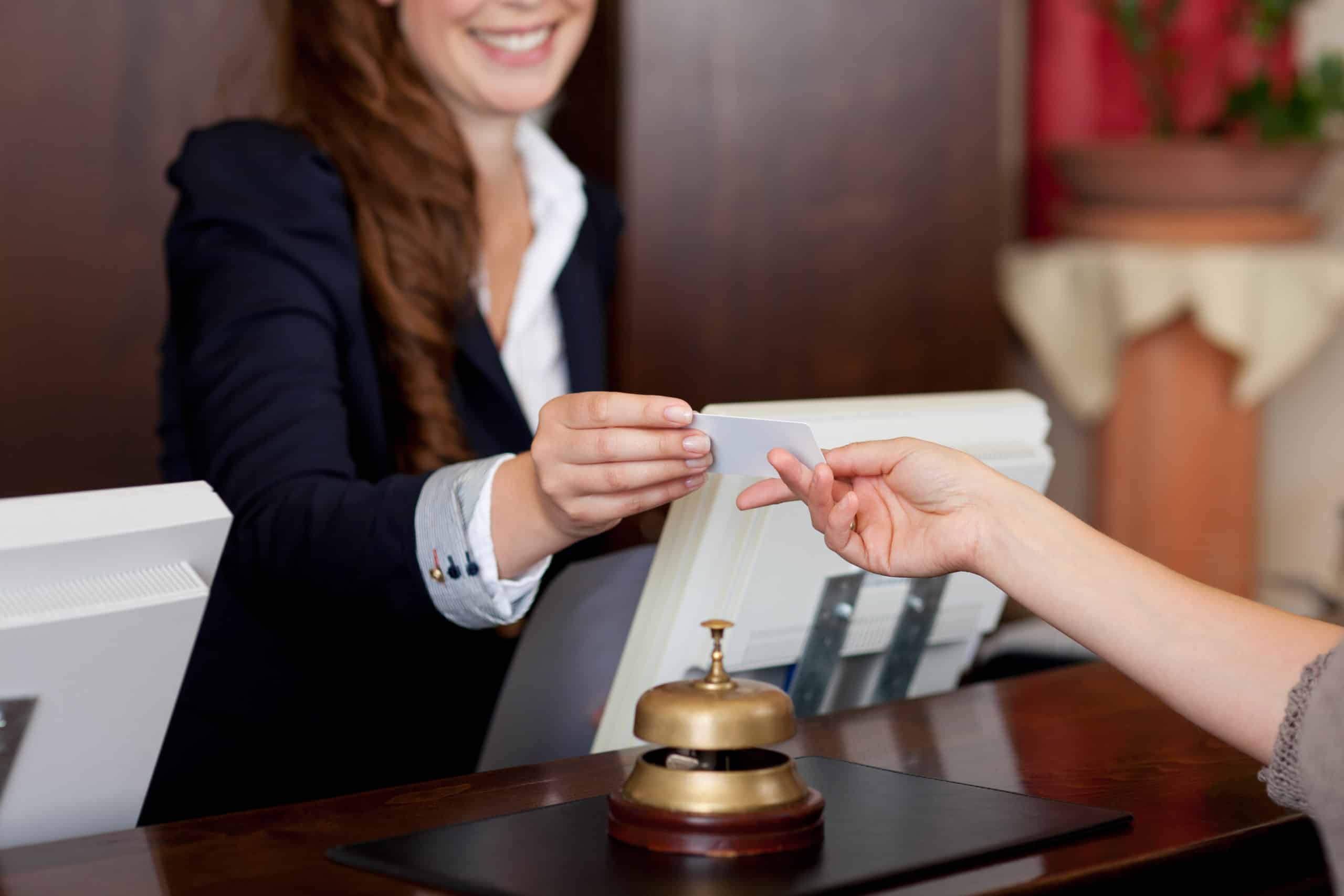 A hotel receptionist hands a keycard to a guest.