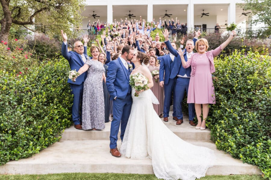 Bride and groom kiss as guests look on and cheer