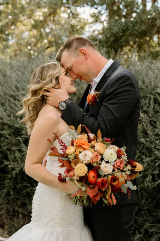 kendall point bride and groom embracing while bride holds bouquet of fall flowers