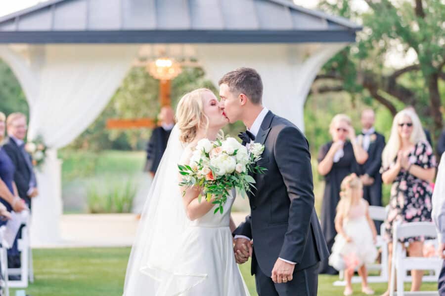 bride and groom kiss at the end of the aisle during kendall point wedding