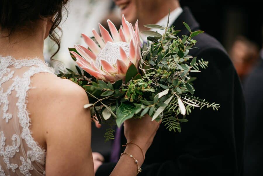 bride holding a single bloom bouquet with king protea flower