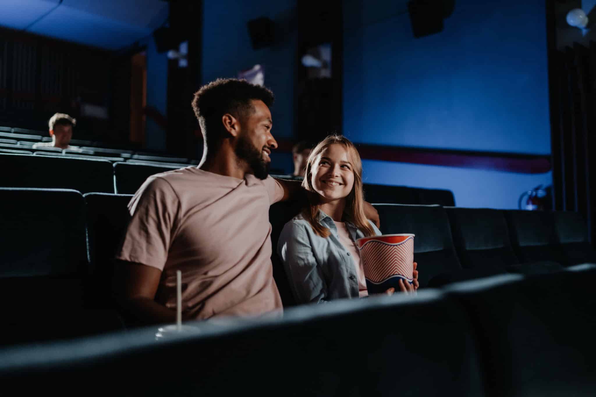 young couple sitting in dark movie theater