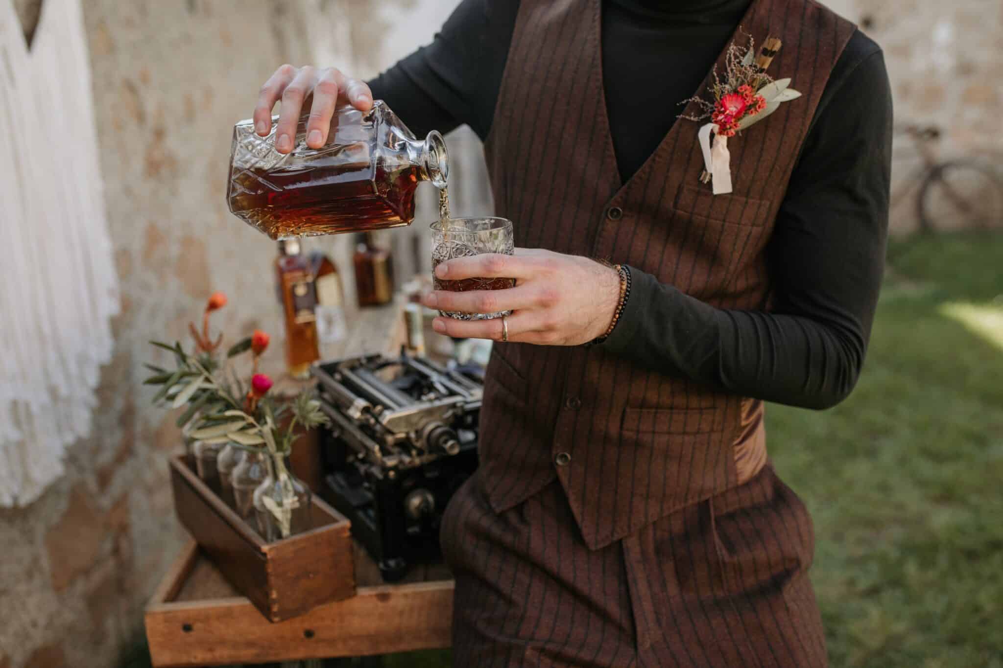 dapper groom pouring whiskey