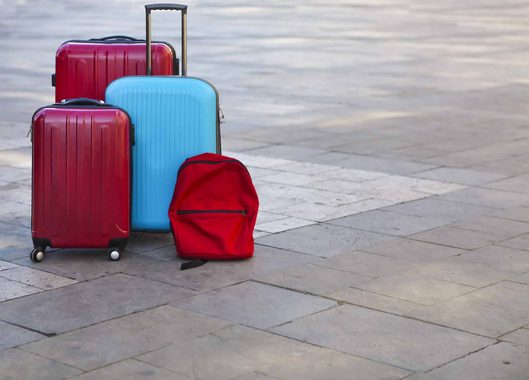 Luggage consisting of three large suitcases and travel backpack on the street. Holiday and travel concept