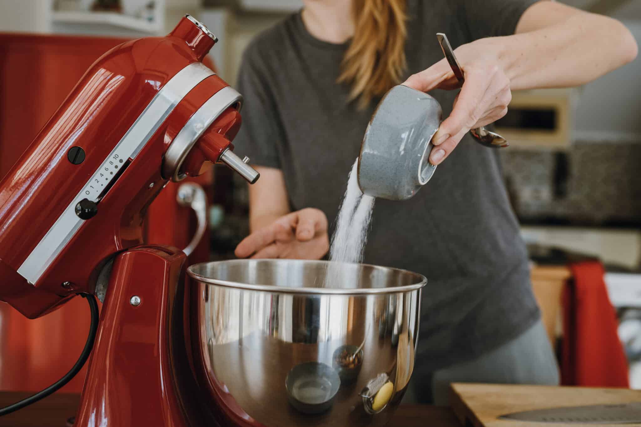 woman pouring sugar into Kitchenaid stand mixer