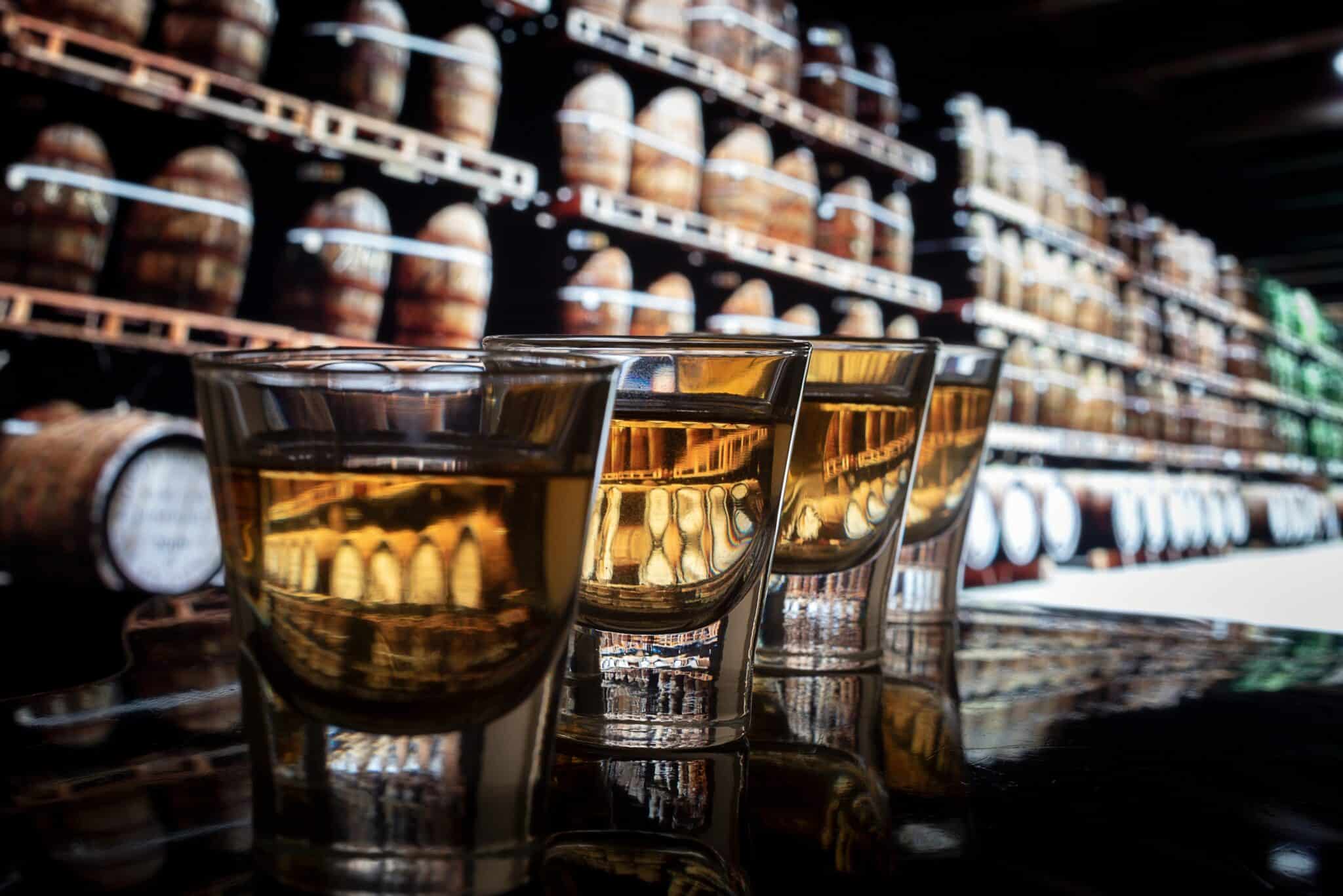 close up of whiskey glasses on bar with barrels in background