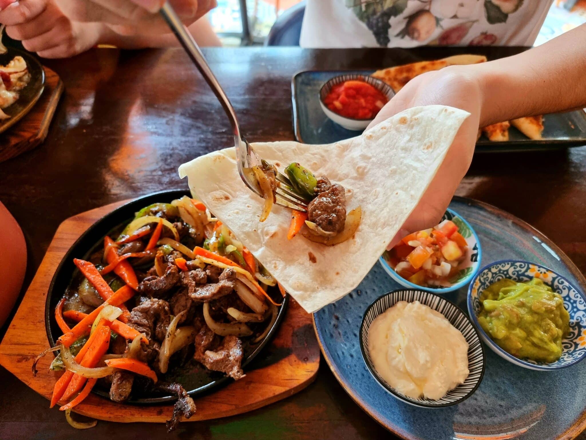 close up of person serving fajitas in restaurant