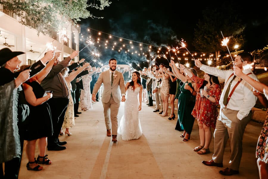 Bride and groom walking outside under guest's sparklers